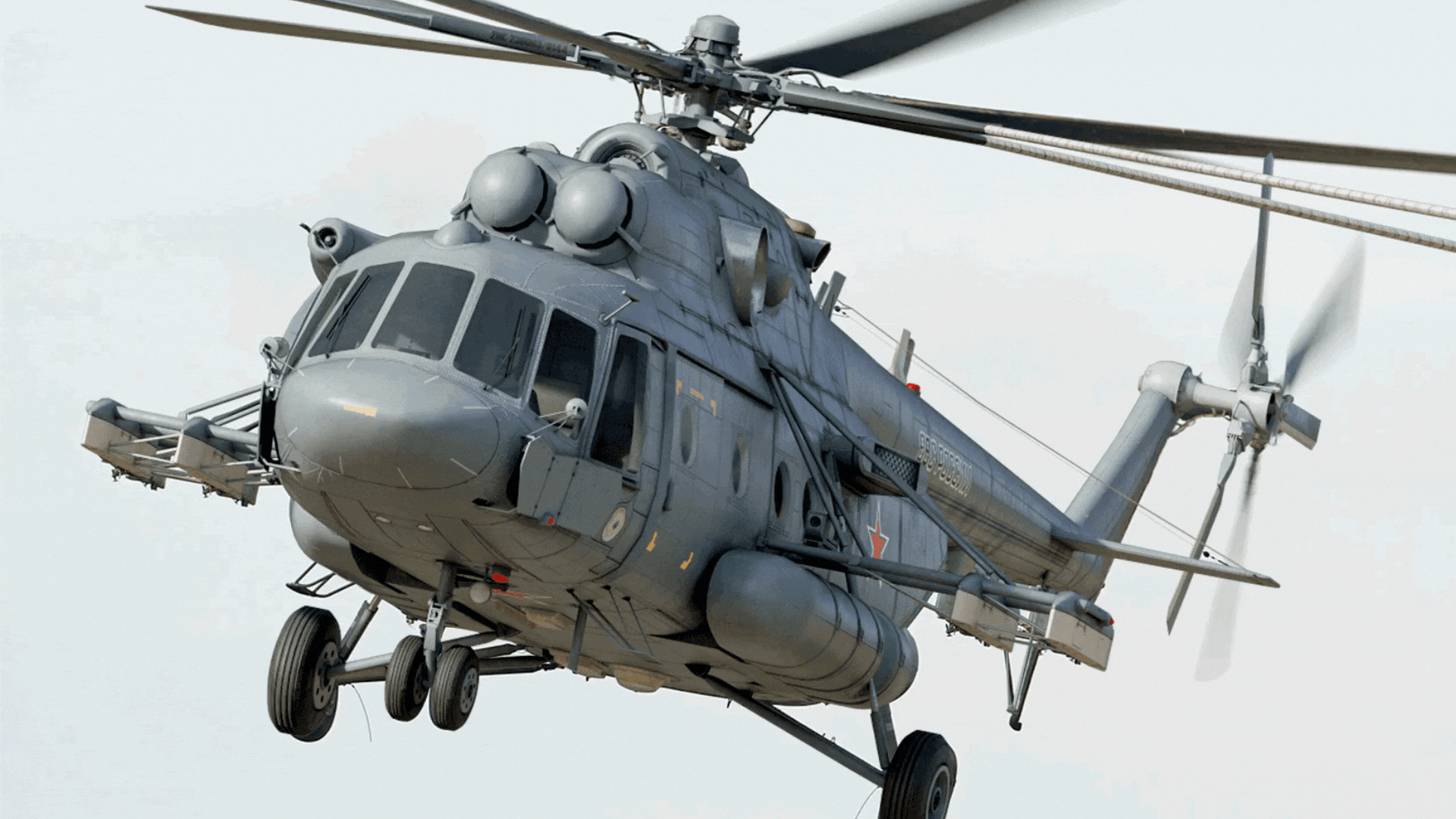 gray helicopter is flying with its rotors spinning against a clear sky background.
