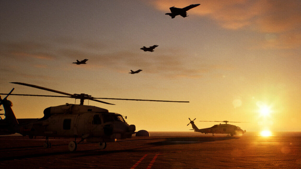 Helicopters on a flight deck with jets flying overhead at sunset, creating a dramatic silhouette against the sky.