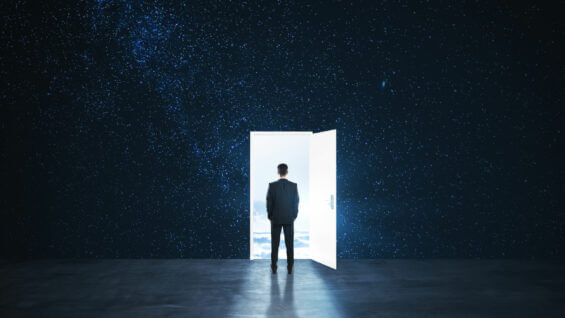 man in a suit stands before an open door leading to a starry sky.