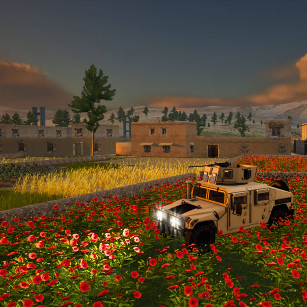 military vehicle is parked in a field of red flowers, with buildings and trees in the background under a sunset sky.